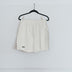 A pair of white running shorts hanging on a hanger against a plain wall.