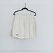 A pair of white running shorts hanging on a hanger against a plain wall.